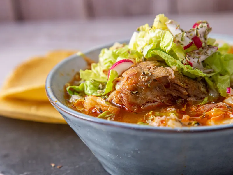 Imagen de referencia: pozole rojo con lechuga, rábano y orégano